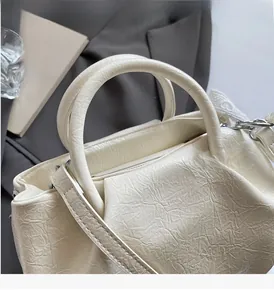 Detail of white pleated bucket bag with sturdy handle and silver hardware accents