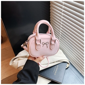 Detail of pink mini bowling bag featuring a silver metal bow and smooth leather texture