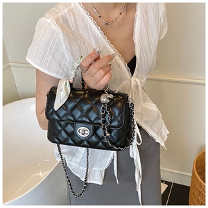 Detail of black quilted leather crossbody bag with silver clasp and silk scarf handle