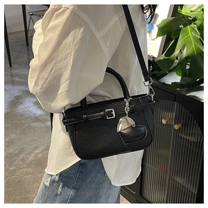 Detail of black lychee grain leather handbag with silver heart charm and metal buckle