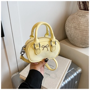 Detail of light yellow mini bowling bag with silver metal bow and adjustable strap