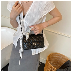 Detail of black quilted leather shoulder bag with chain strap and decorative floral scarf