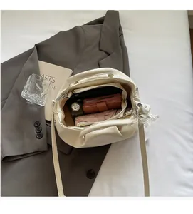 Top view of cream bucket bag showing spacious interior with wallet, perfume and umbrella