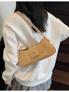 Sac baguette brillant en similicuir marron clair avec logo argenté sur un modèle