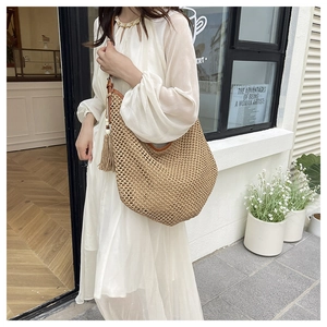 Detail of straw woven hobo bag featuring decorative tassels and wooden bead ornaments