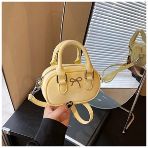 Close-up of bright yellow mini bowling bag with a metal bow and adjustable strap