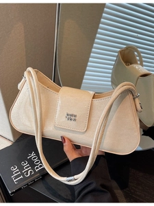 Sac sous le bras chic en cuir verni crème avec logo argenté sur un décor de livre élégant