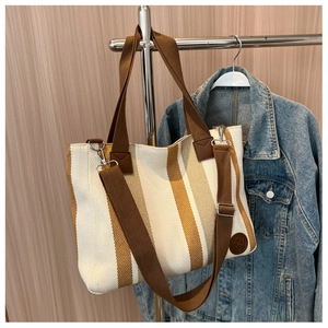 Detailed macro view of a striped canvas tote bag with adjustable brown shoulder straps