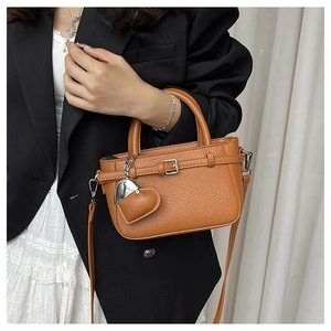 Caramel lychee grain leather crossbody bag with heart charm shown on model in studio