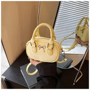 Close-up of a mini yellow bowling bag with silver bow detail and detachable strap