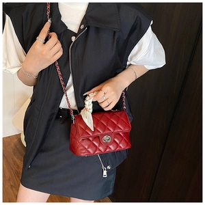 Red quilted crossbody bag with silver hardware and silk scarf handle on model