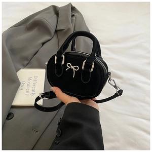 Detailed shot of black mini bowling bag with silver bow accent and velvet texture