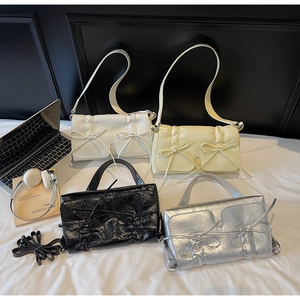 Détail de sacs à bandoulière plissés avec nœuds en blanc, jaune, noir et argent brillant