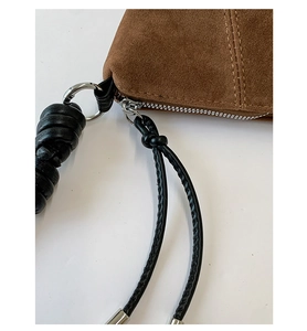Détail de la sacoche en daim marron avec fermeture éclair en métal argenté et double couture