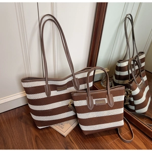 Detail der gestreiften gewebten Tasche mit braunen Ledergriffen und Markenlogo-Etikett
