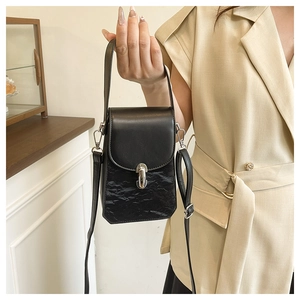 Détail d'un sac bandoulière noir avec cuir lisse et texture plissée élégante