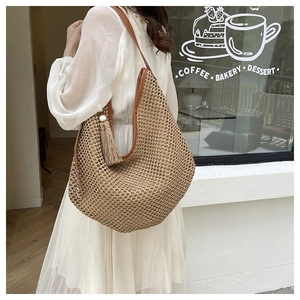 French woven straw tote bag with brown leather handles and decorative tassel detail