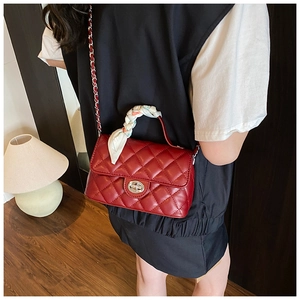 Detailed view of red quilted leather crossbody bag with chain strap and silk scarf handle