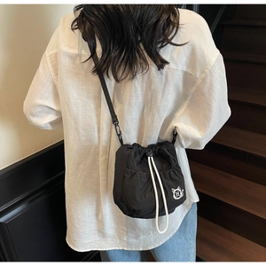 Lifestyle view of a black drawstring bucket bag with a cat logo on a model