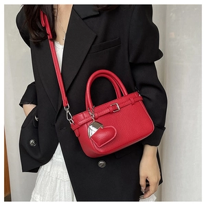 Detail of red litchi texture mini tote bag with heart charm on a black blazer