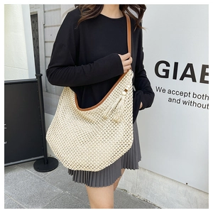 Detail view of the hand-woven texture and leather strap on a cream straw hobo bag