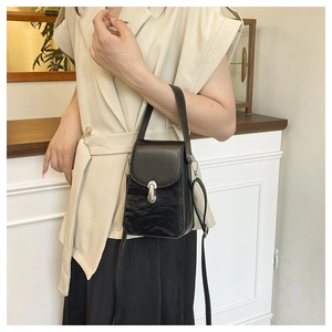 Détail du petit sac noir avec textures mixtes, boucle argentée et bandoulière