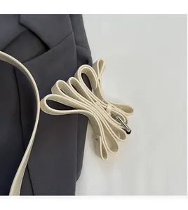 Détail de la bandoulière en cuir crème lisse avec des crochets en métal argenté poli