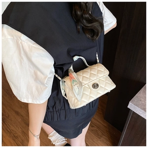 Detail of cream quilted crossbody bag with decorative geometric silk scarf on handle