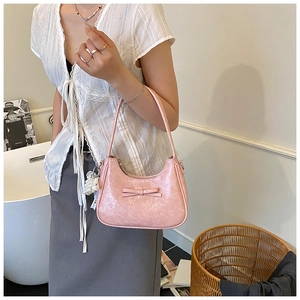 Dettaglio della borsa a mano rosa con fiocco, finitura lucida ed elegante ciondolo di perle
