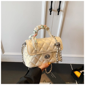 Close-up of cream quilted handbag with silk scarf handle and metal chain detail