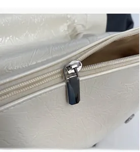 Gros plan sur la fermeture éclair argentée et le cuir texturé du sac fourre-tout