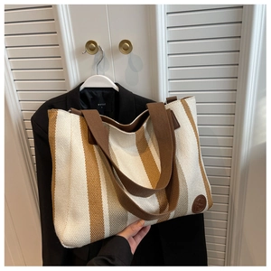 Close-up of cream canvas tote bag with brown vertical stripes and wide shoulder strap