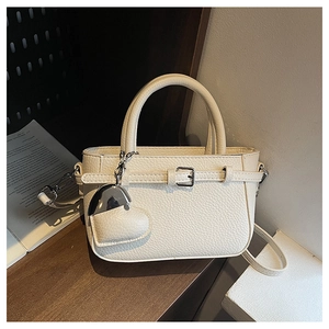 Detail of cream lychee texture leather handbag with heart-shaped metal pendant charm