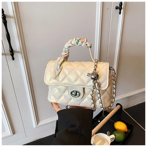 Detail of white quilted crossbody bag with silk scarf handle and silver chain strap