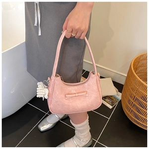 Rosa strukturierte Hobo-Tasche mit Schleife und Perlenanhänger in der Hand