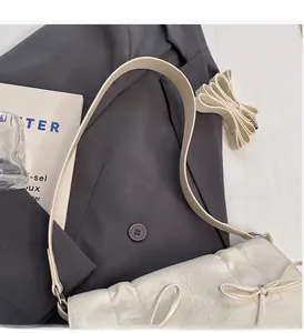 Détail du sac crème avec nœud montrant la texture PU froissée et les bandoulières réglables
