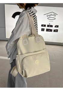 Detailansicht des cremeweißen Nylon-Rucksacks mit großer Fronttasche und Tragegriff