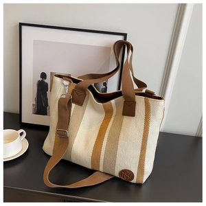 Detail of striped canvas tote bag with brown woven handles and adjustable shoulder strap