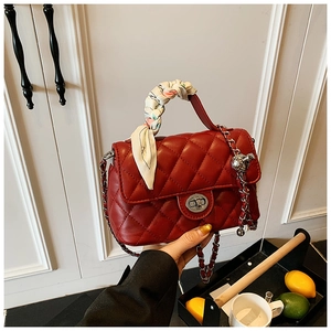 Close-up of red quilted leather bag with silver buckle and decorative silk scarf handle
