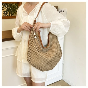 Detailed close-up of straw hobo bag with hollow weave and brown leather trim detailing