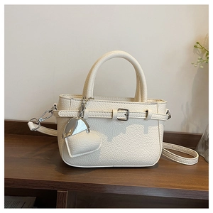 Close-up of beige lychee texture leather mini tote with heart pendant and silver hardware