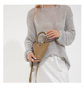 Détail du sac seau en cuir camel avec design asymétrique et logo de marque argenté