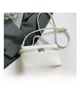 Close-up of white lychee pattern leather square bag with silver double zipper and strap