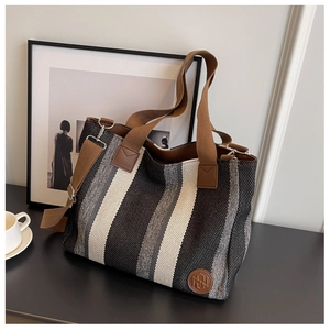 Detail of striped canvas tote with brown woven handles and detachable shoulder strap