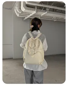 Detailansicht eines cremeweißen Nylon-Rucksacks mit großer Vordertasche für den Alltag