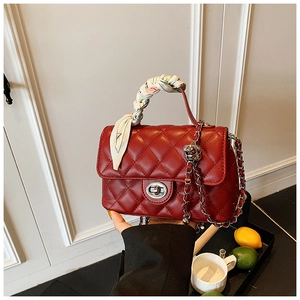 Detail of red quilted crossbody bag with silk scarf wrapped handle and silver hardware