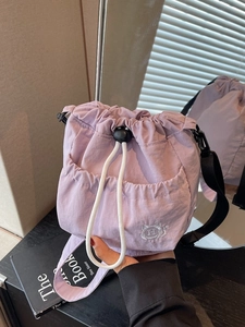 Lavender nylon drawstring bucket bag with adjustable black strap and white embroidery logo