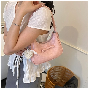 Detailaufnahme der rosa gefalteten Schultertasche mit Schleife und Herz-Perlenanhänger