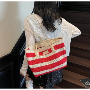 Detail der rot-weiß gestreiften gewebten Tasche mit Lederriemen an einem Modell