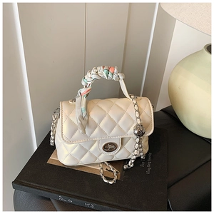 Close-up of beige quilted bag with silk scarf handle and adjustable metal chain strap